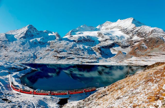 Il trenino rosso del Bernina lungo la riva del lago bianco e del Piz Cambrena