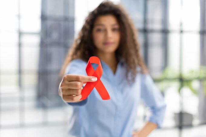donna con in mano il fiocco rosso della giornata mondiale contro l'aids